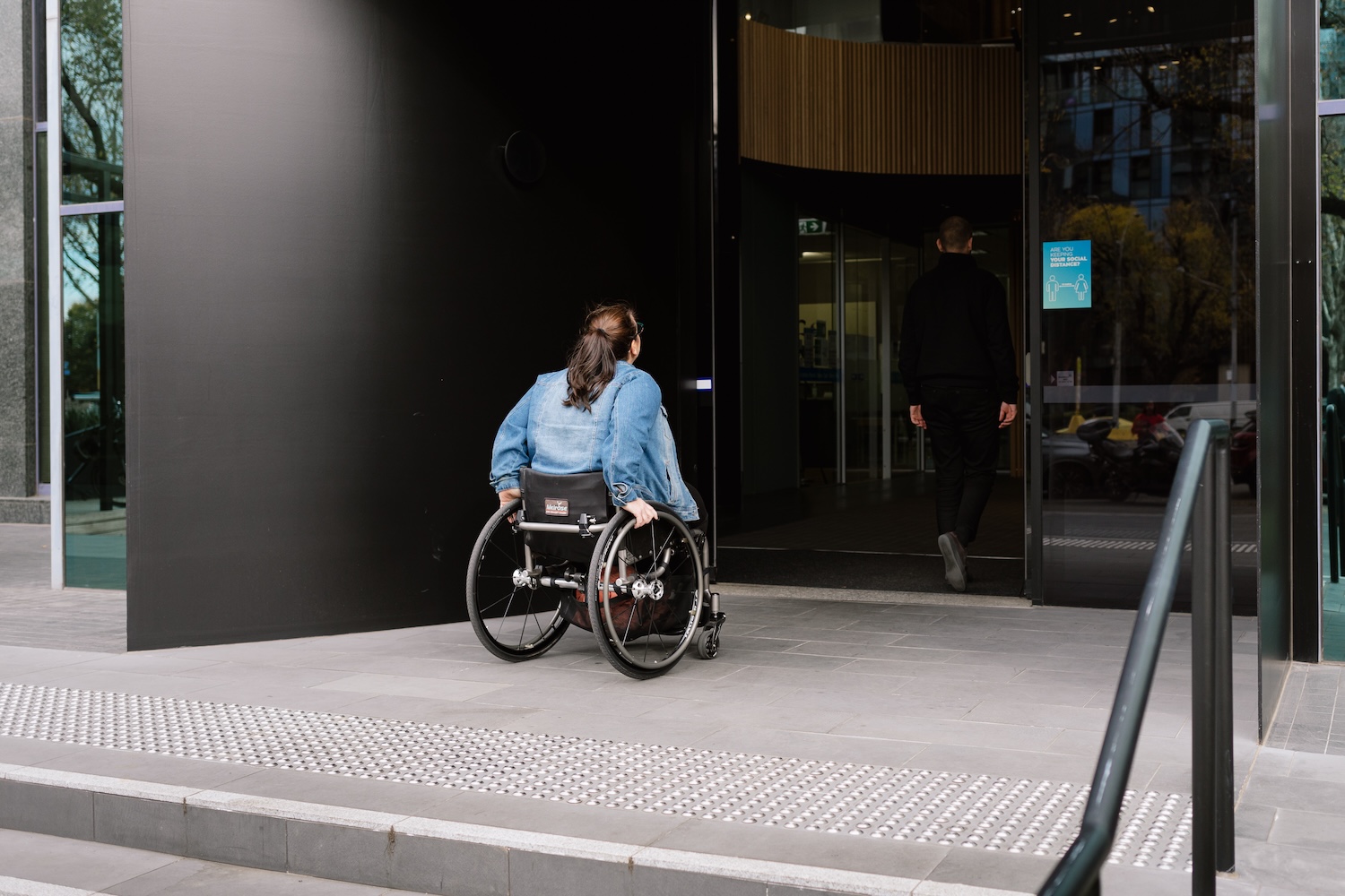 Women who is a wheelchair user entering building using automatic door