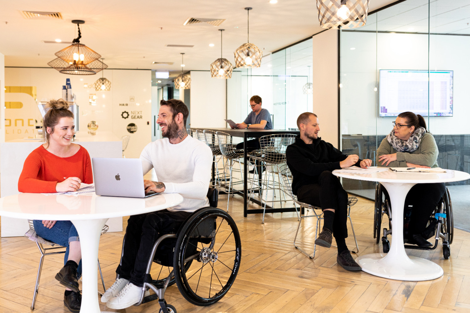 Men and women sitting around small tables in an office environment