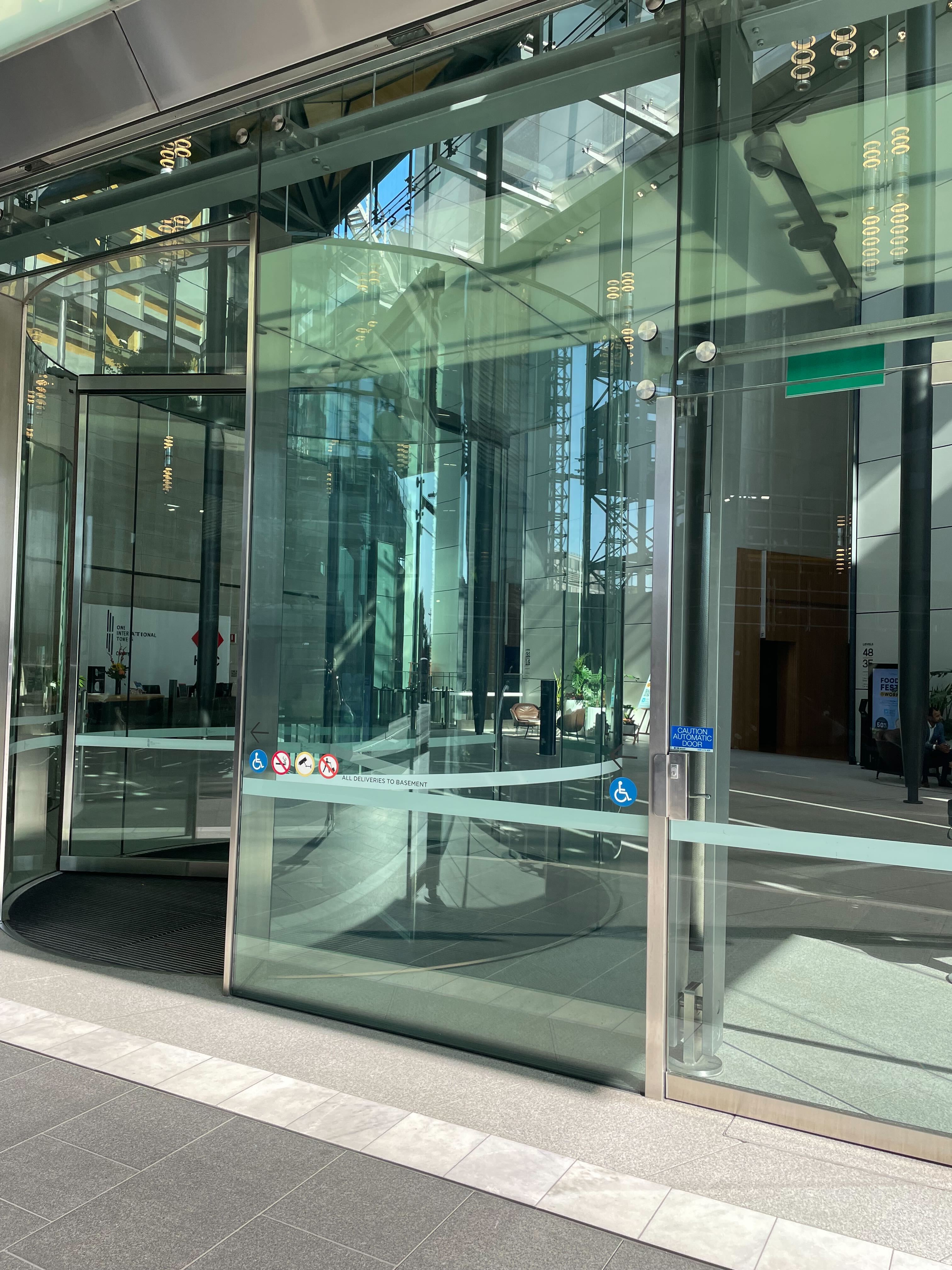 Image of glass revolving doors and an accessible swinging door to its side. 