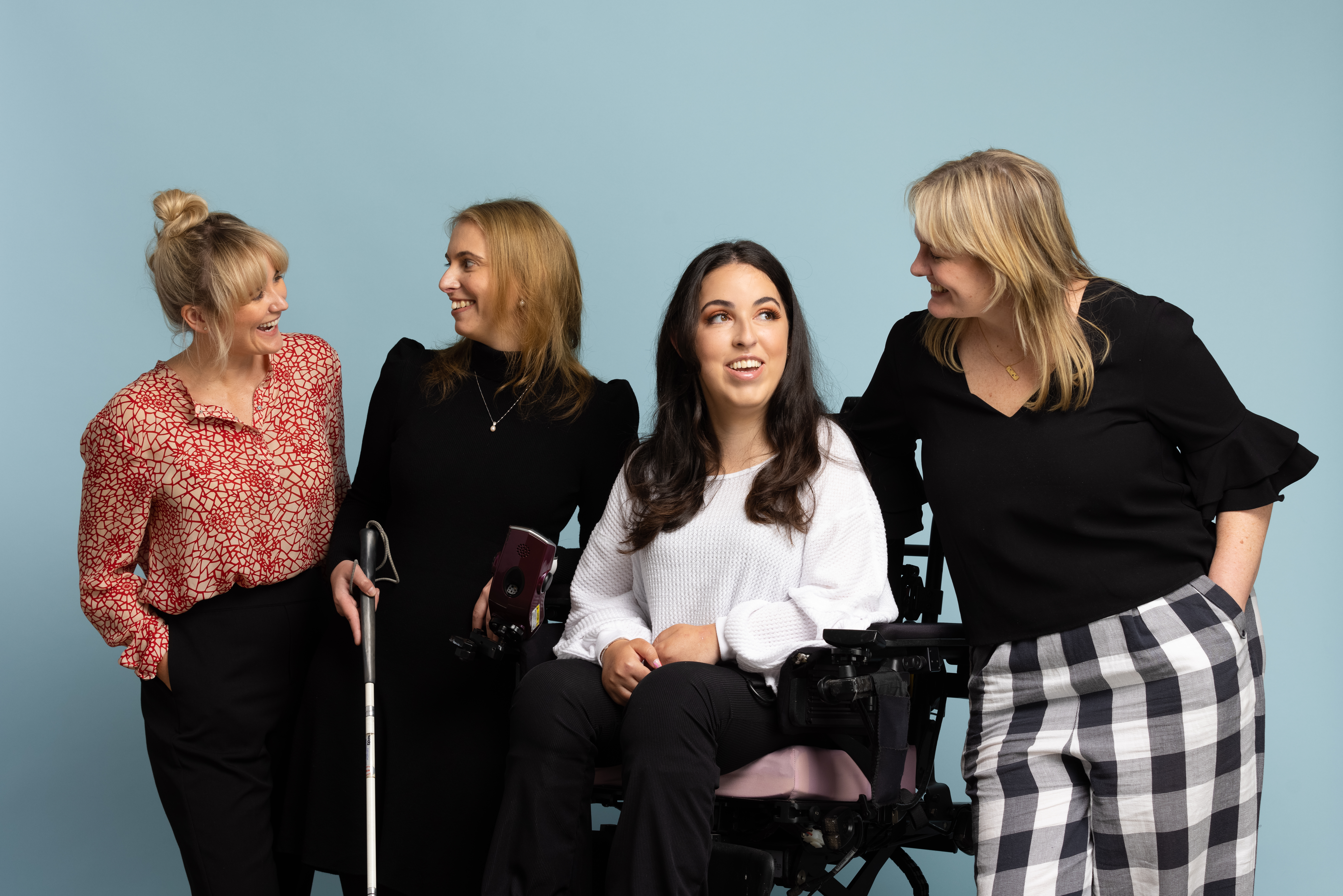 Four women in a line smiling at one another