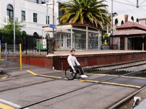 heath crossing the road at Prahran station in Melbourne while navigating the gaps in the footpath that train tracks create