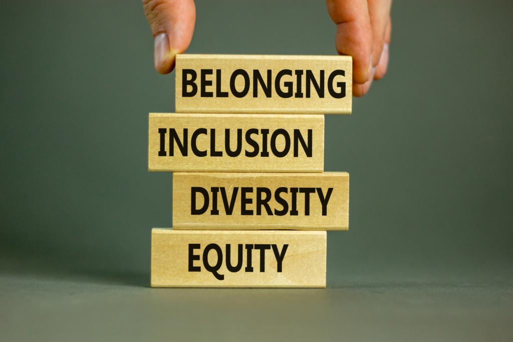 An image depicting the game Jenga, where each block shows words in black bold font. The words are: belonging, inclusion, diversity, and equity.