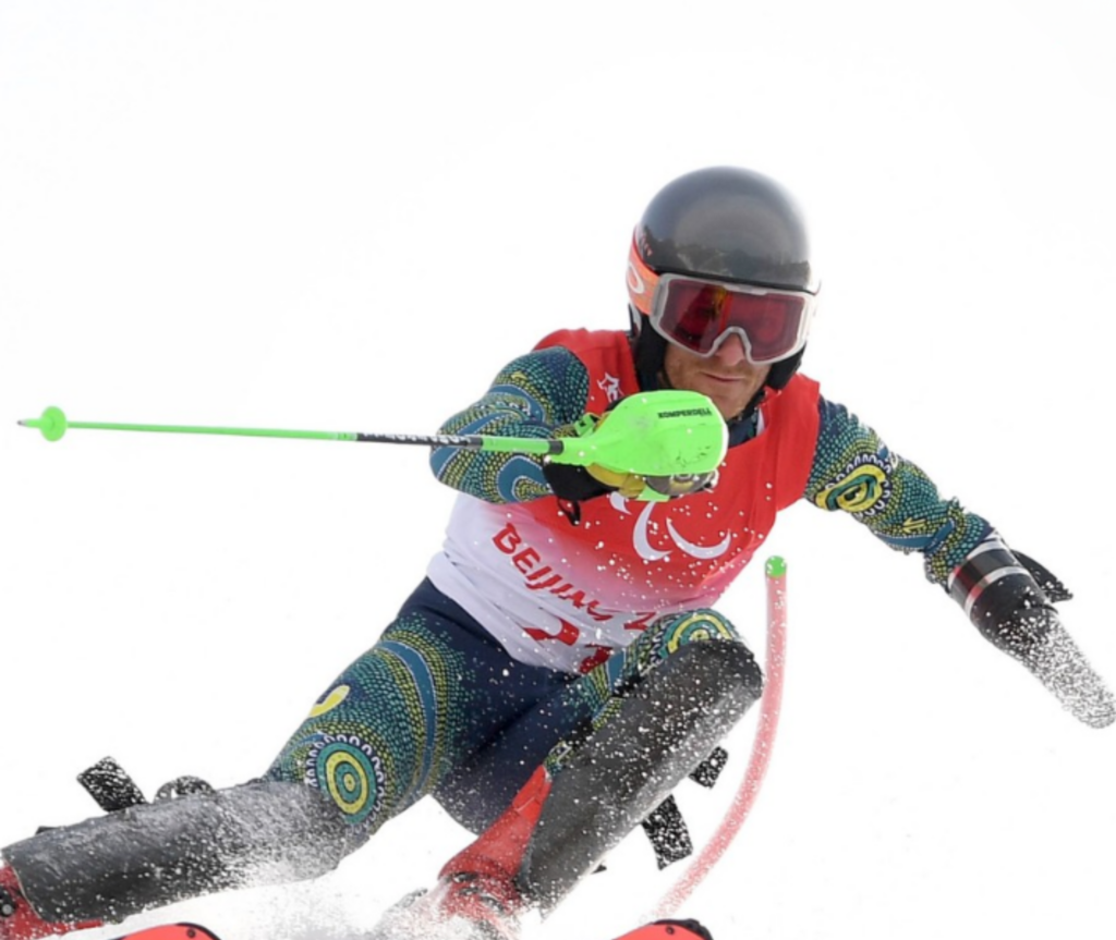 An alpine skier in action, wearing Australian national team gear, is captured as he is about to make a turn in the snow.
