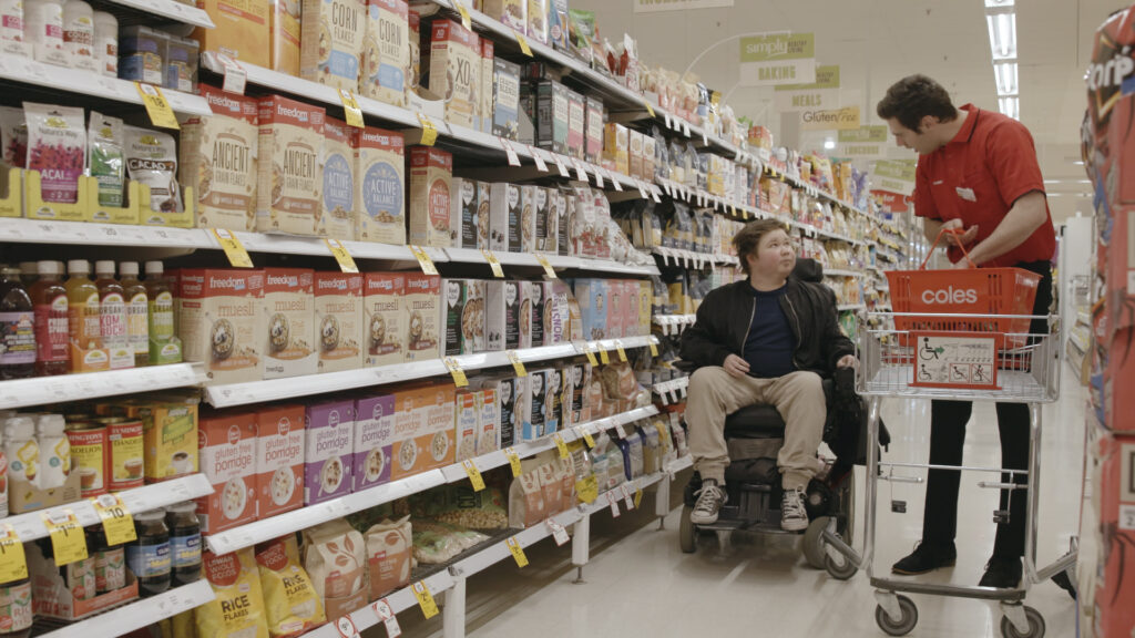 Man in a wheelchair entering a building with automatic glass doors.