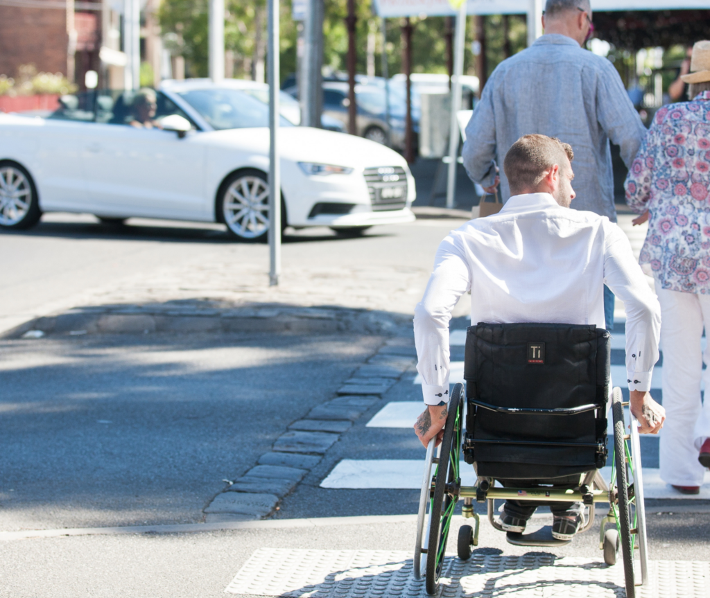 A man on wheelchair crossing a street.