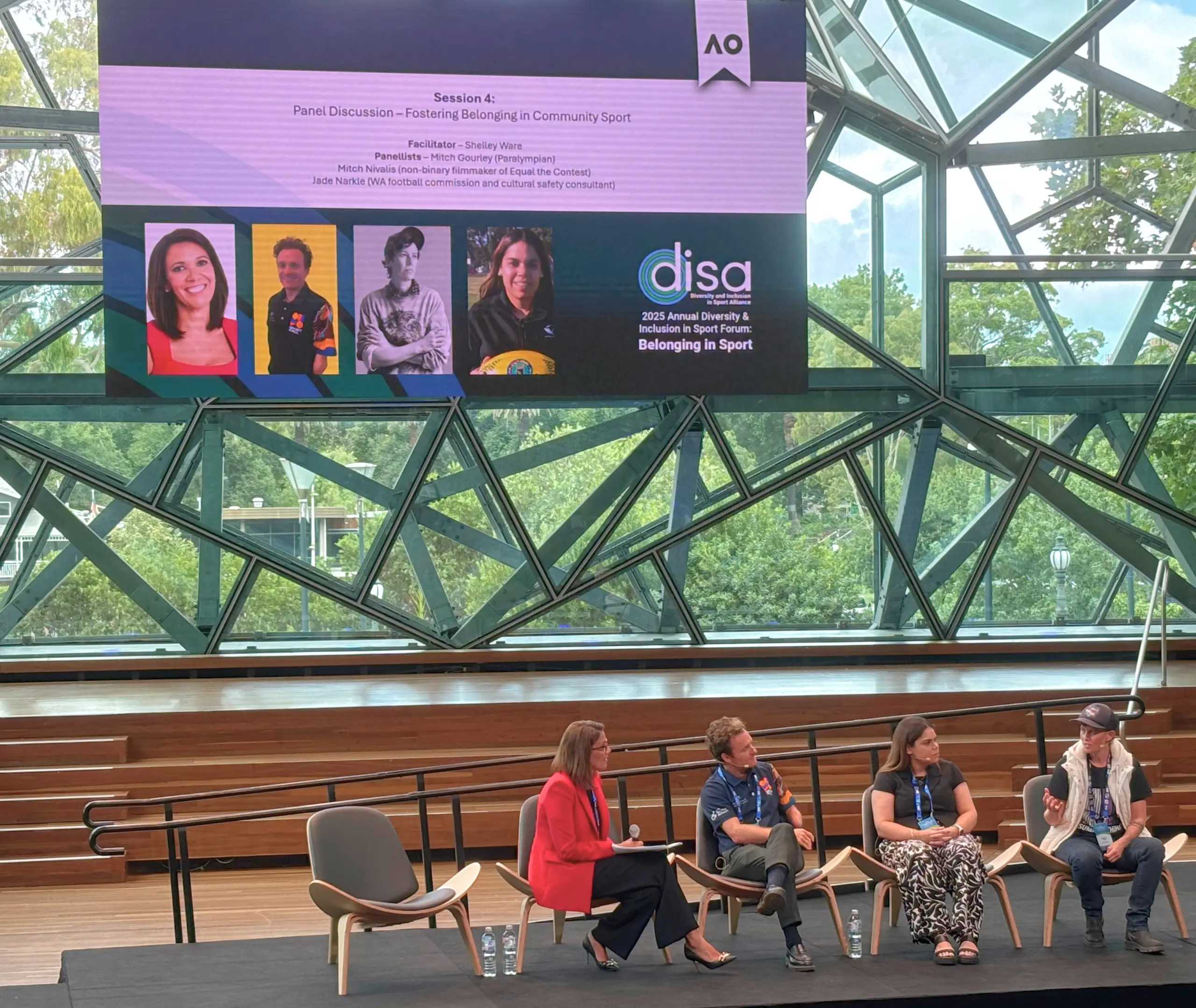 The image shows a large screen at the DISA Forum with bold white text on a dark background that reads: "If sports isn't about creating belonging and connection, then what are we really playing for?"