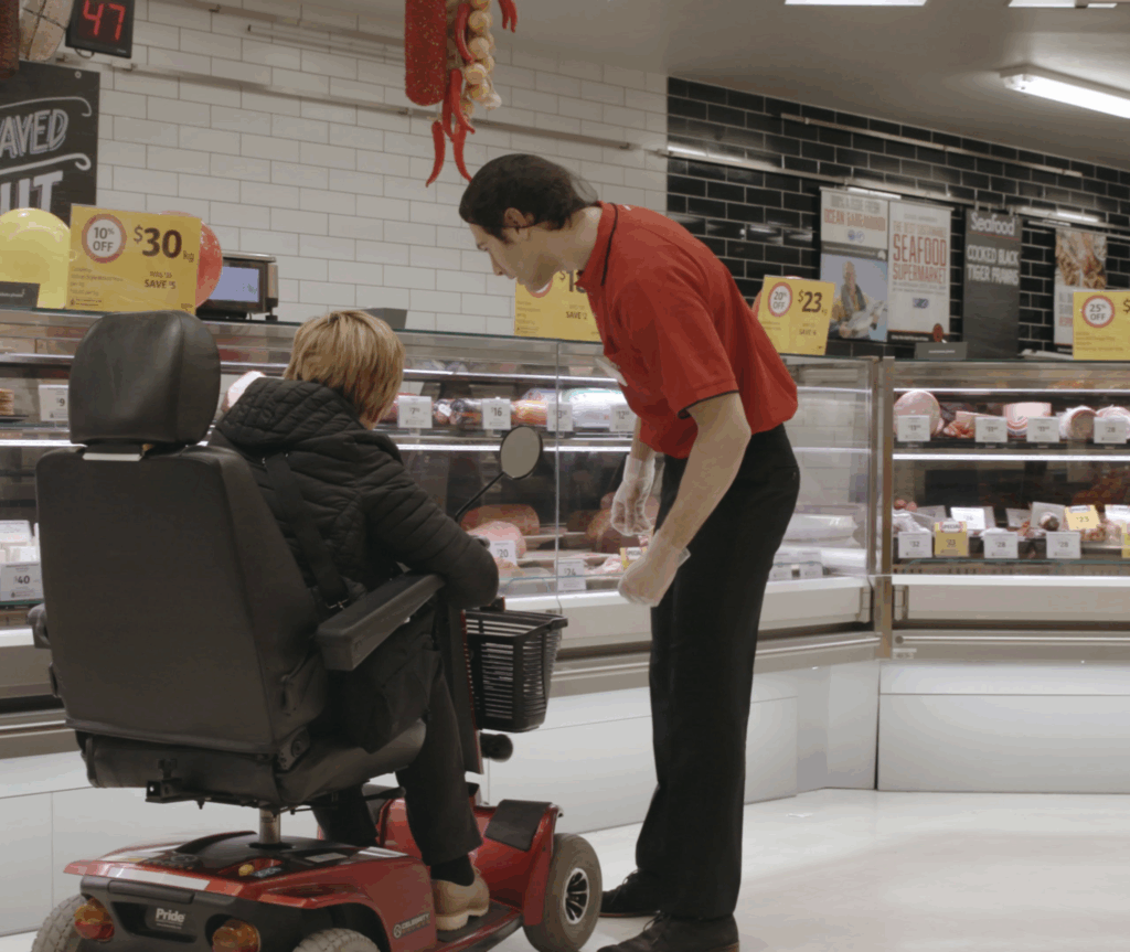 A Coles Grpoup employee helping a person on wheelchair