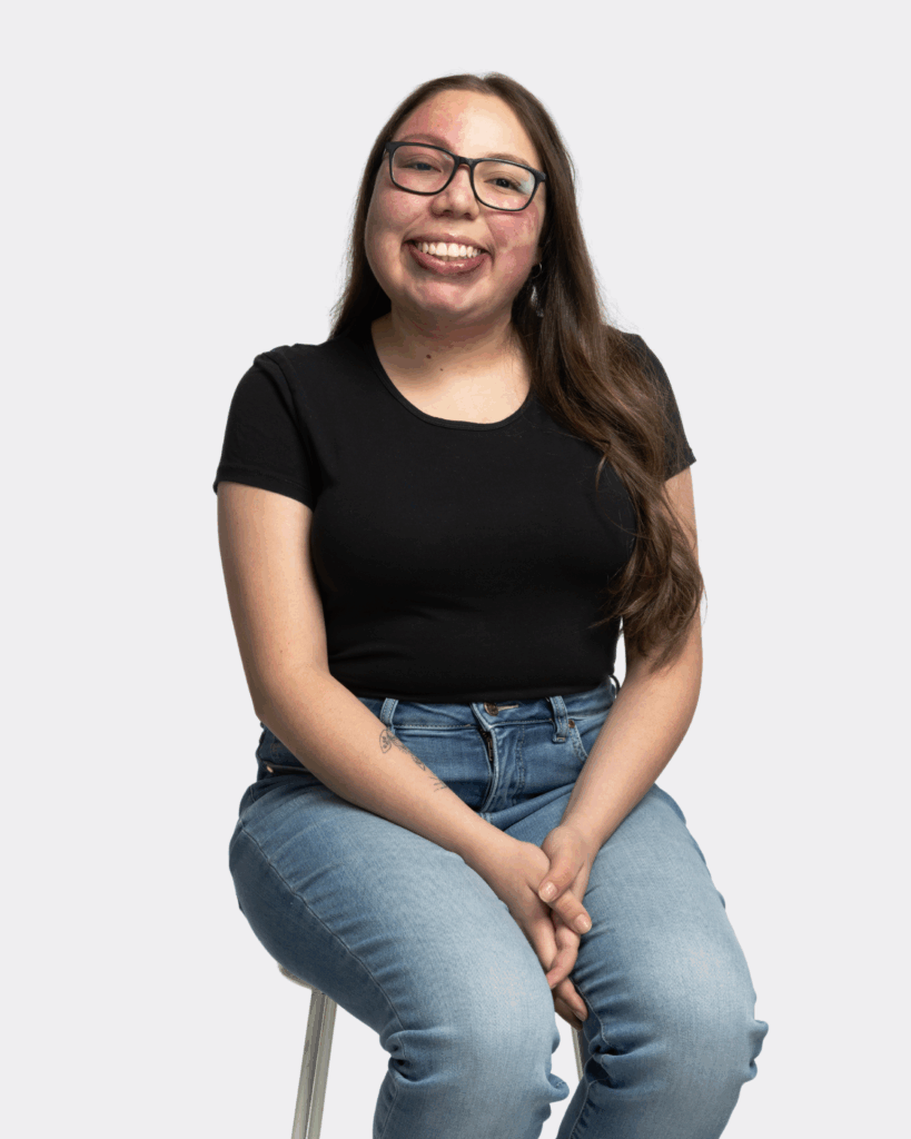 Celine Ramos, a young woman wearing jeans and black shirt looking at the camera and smiling.