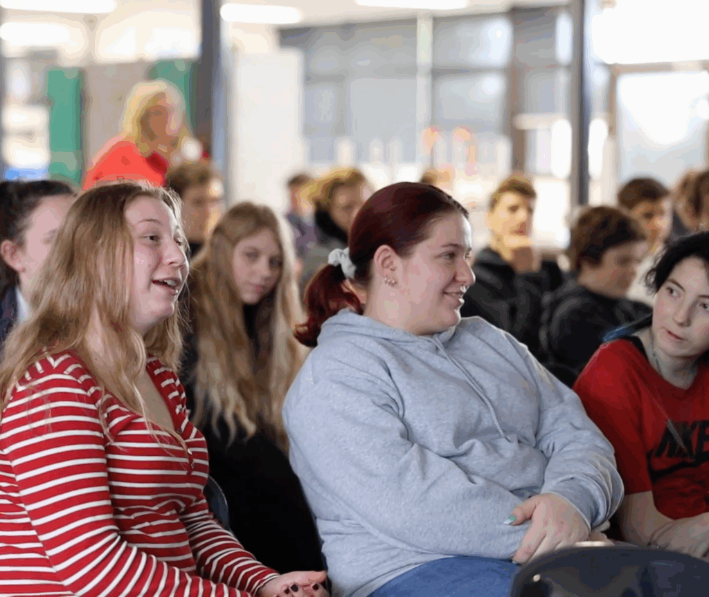 Group of children sitting in large room, similing and listening