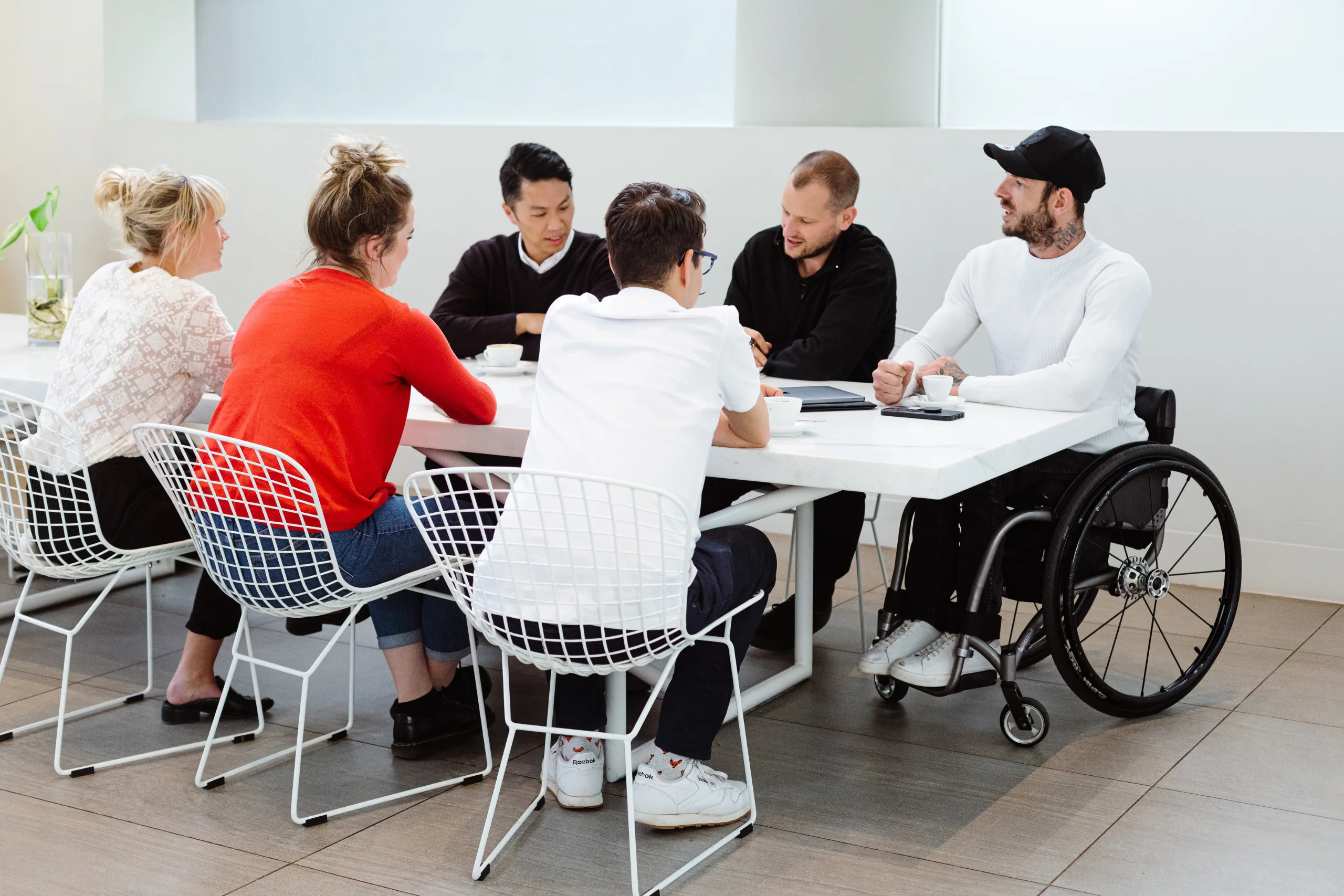 Group discussion in a meeting room with one person sitting on the wheelchair listening