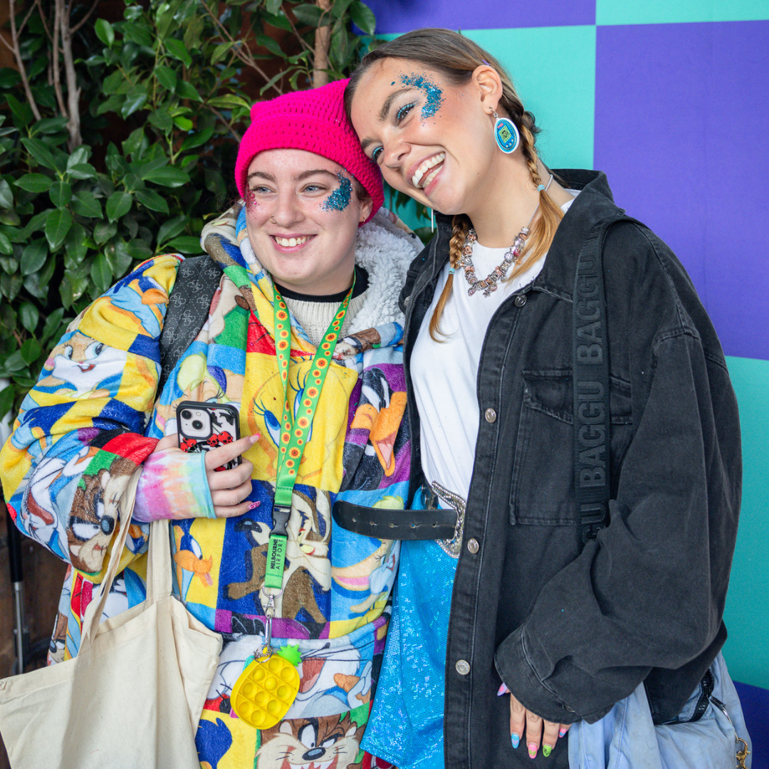 Two people smiling together at an event, wearing colourful outfits.
