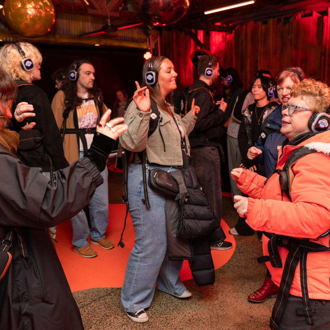 Group of people wearing headphones and tactile vest dancing together.
