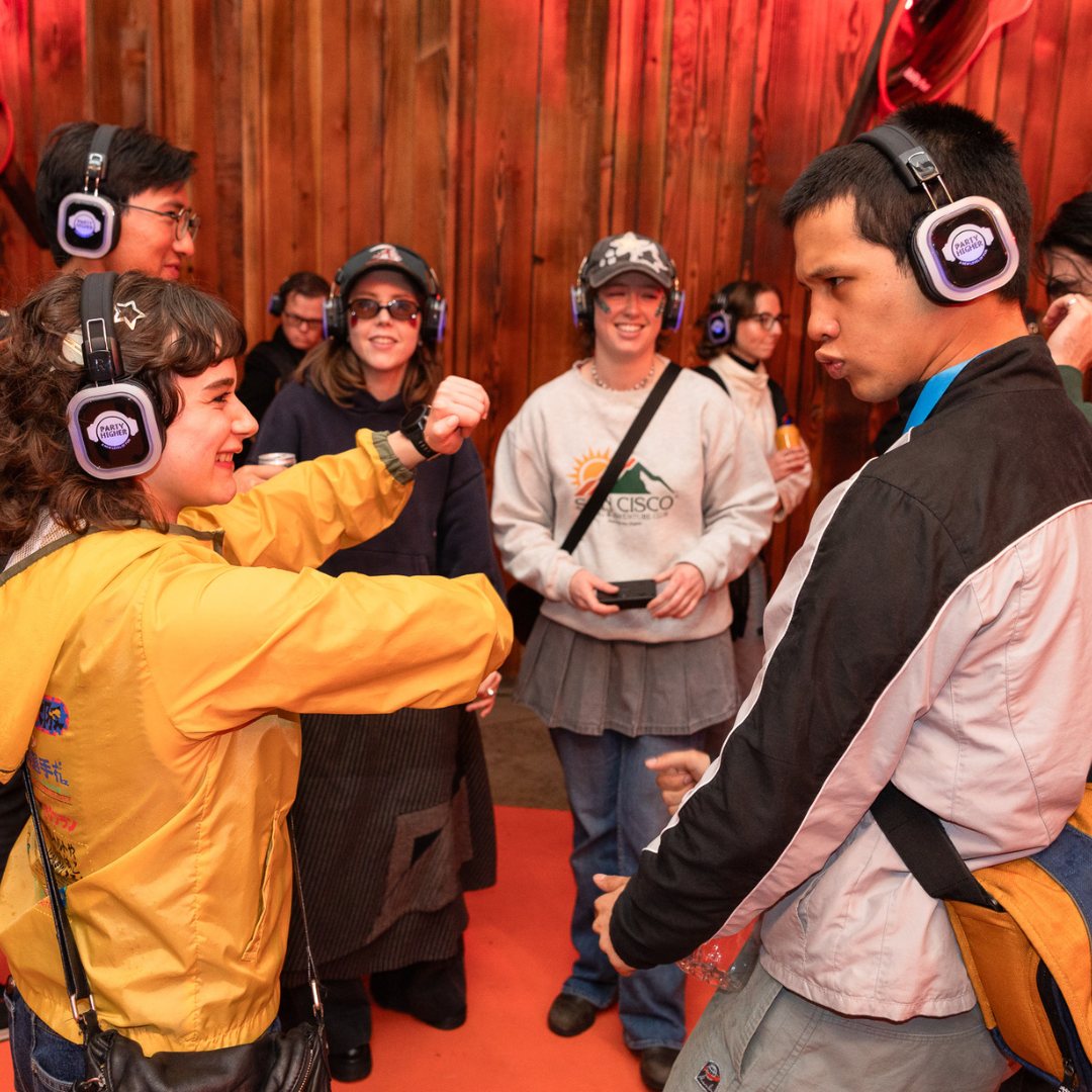 Group of people wearing headphones and tactile vest dancing together.