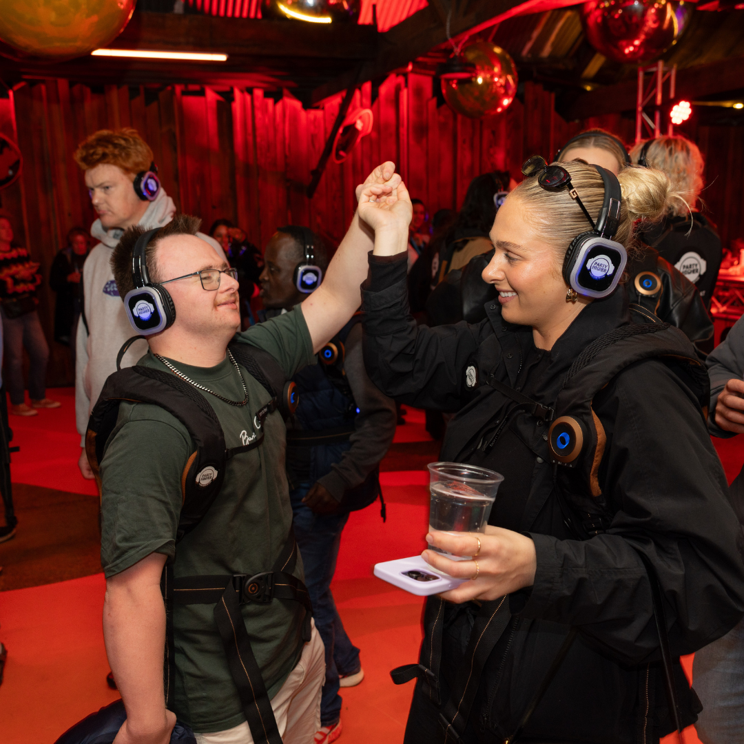 Two people holding hands and dancing at a silent disco.